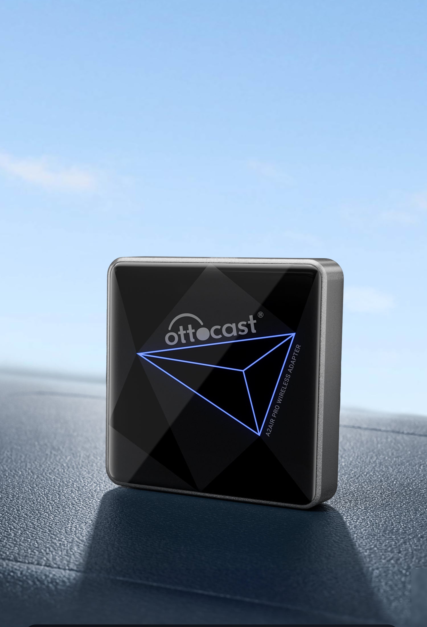 Ottocast wireless adapter with sleek black design placed on car dashboard under clear blue sky