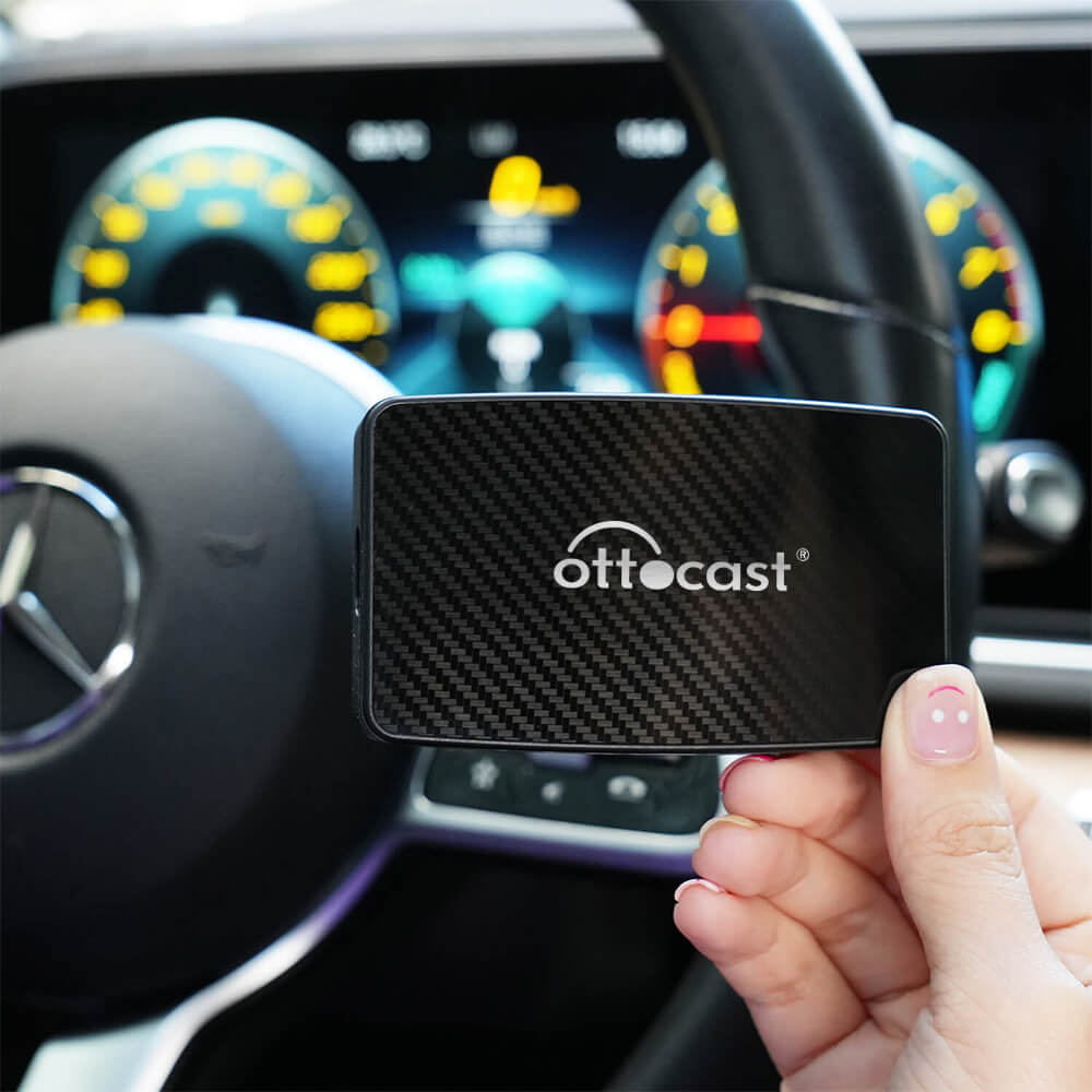 Wireless CarPlay and Android Auto adapter ottocast device held inside Mercedes-Benz car with dashboard in background