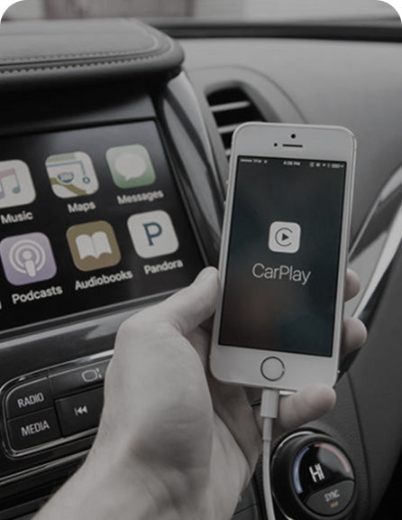 iPhone connecting to Apple CarPlay in car dashboard, displaying apps like music, maps, messages and podcasts