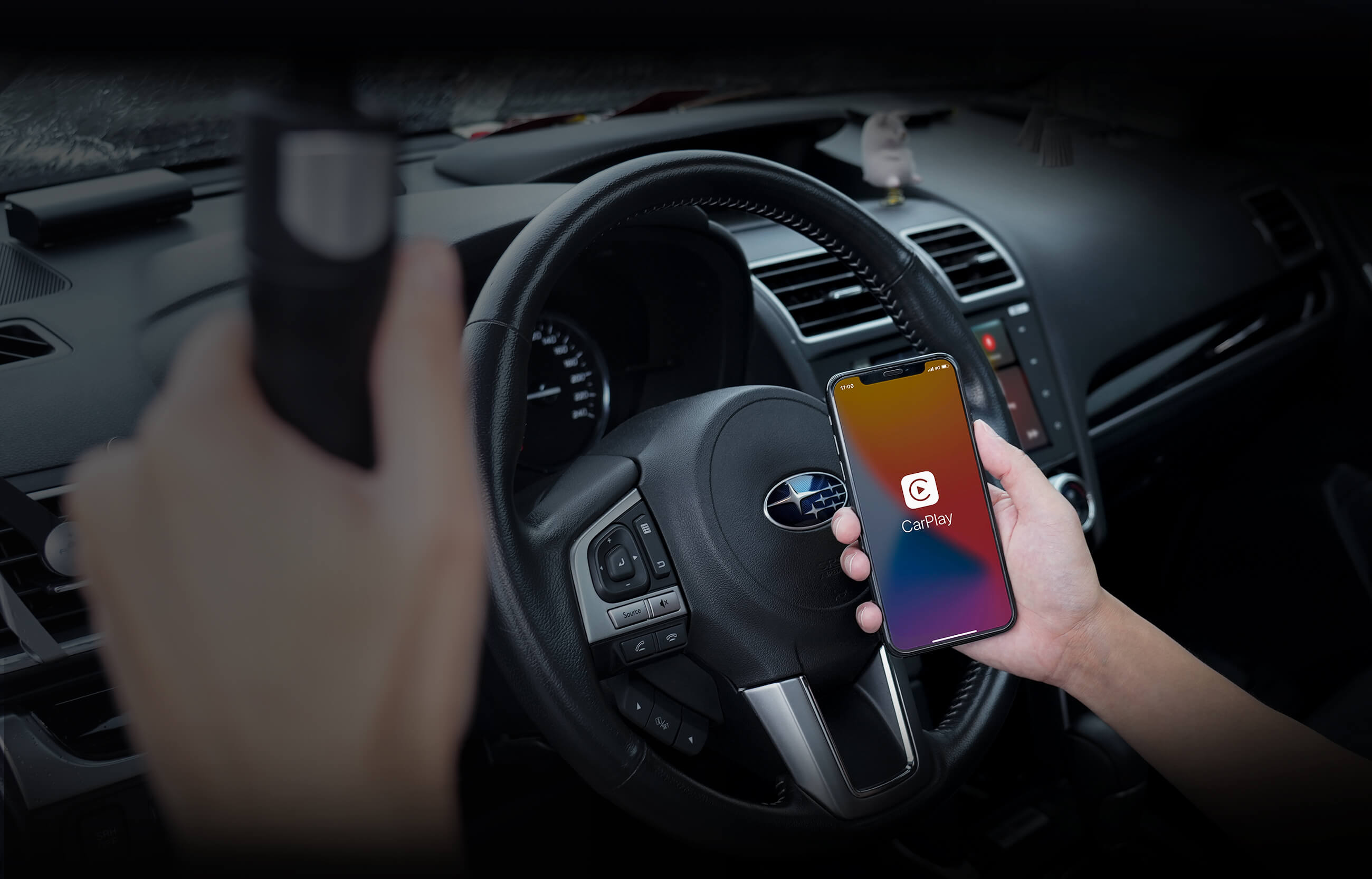 Driver holding smartphone with Apple CarPlay interface inside Subaru vehicle for wireless connection