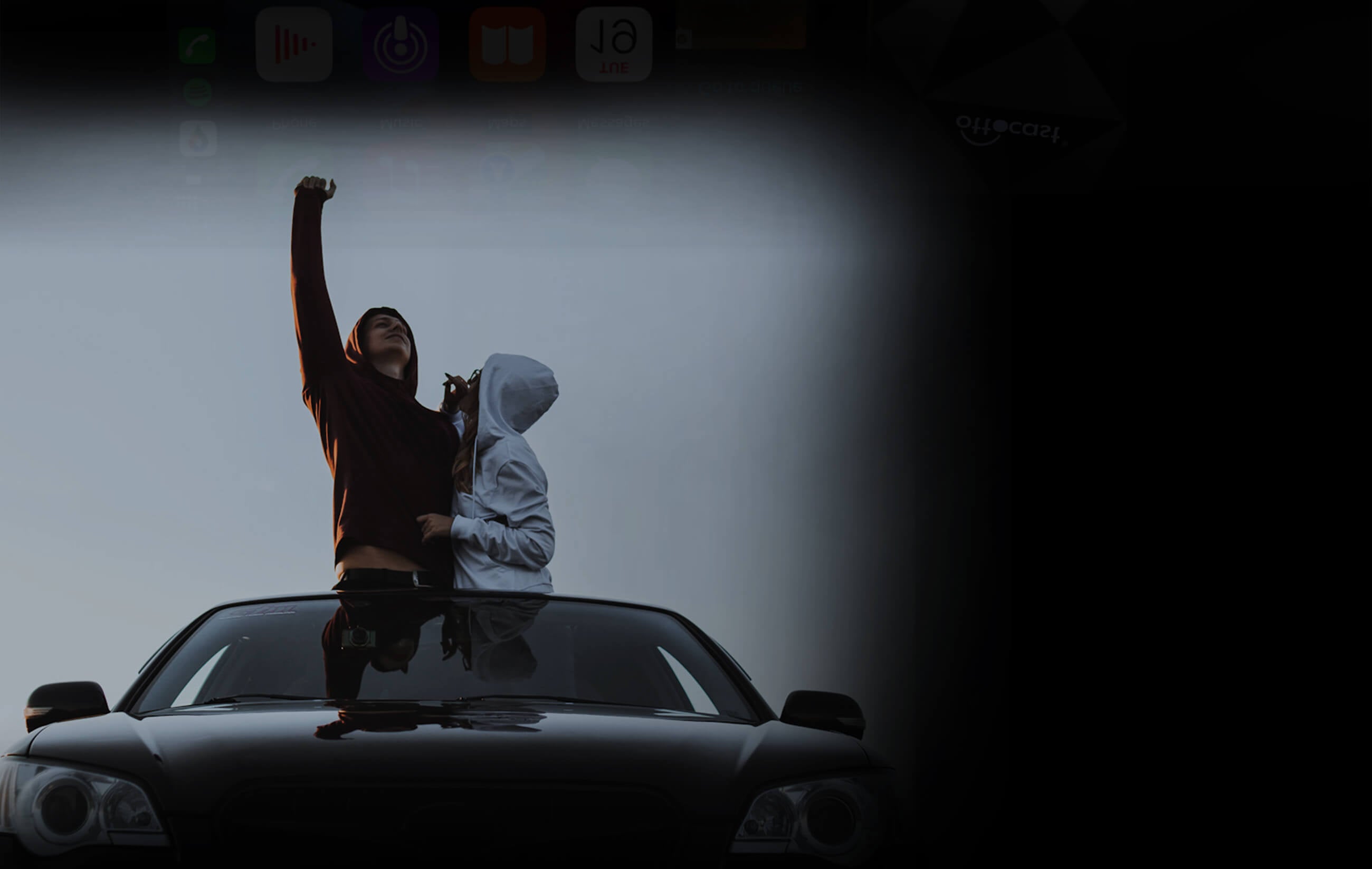 Young couple standing through car sunroof celebrating road trip with Ottocast wireless CarPlay and Android Auto adapter